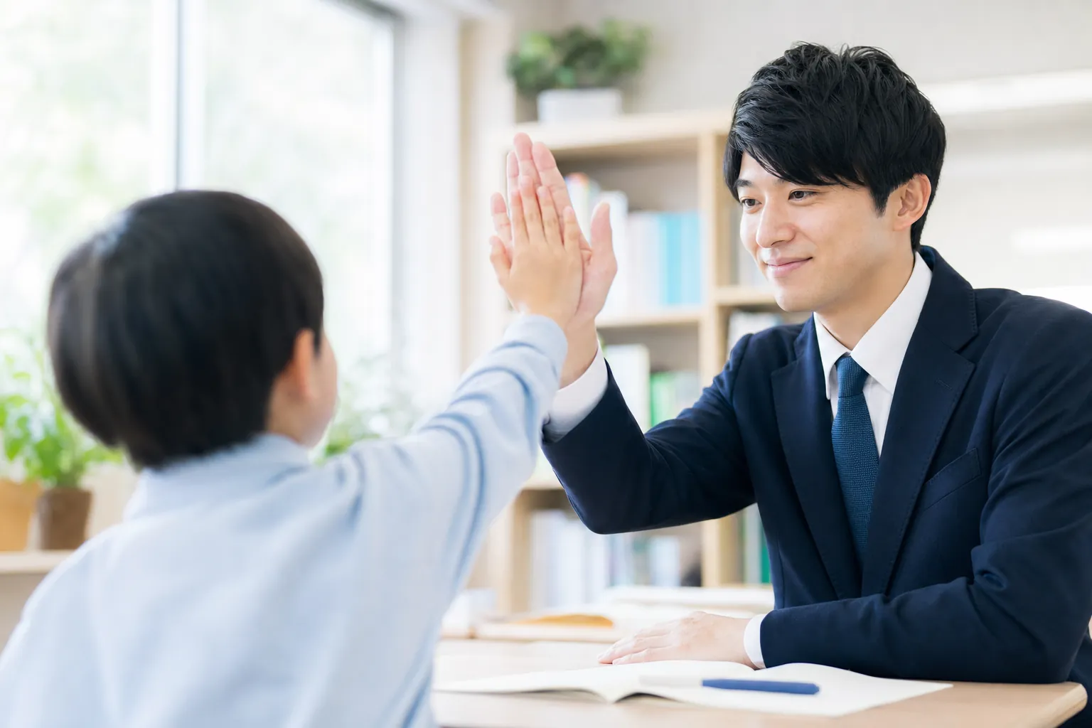 小学生が講師とハイタッチする瞬間。笑顔・明るい教室